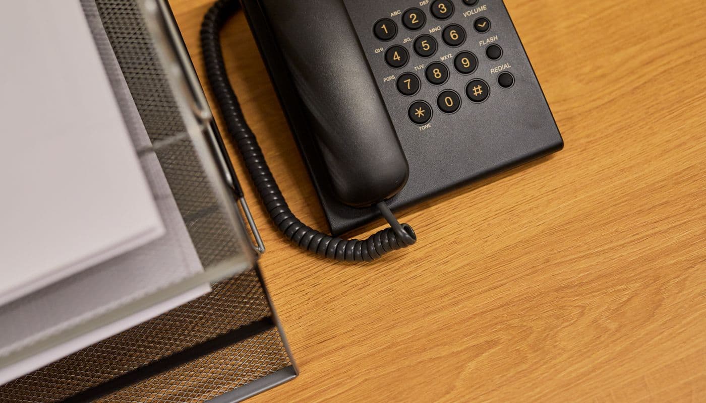 Et skrivebord med telefon, kalender og papirer